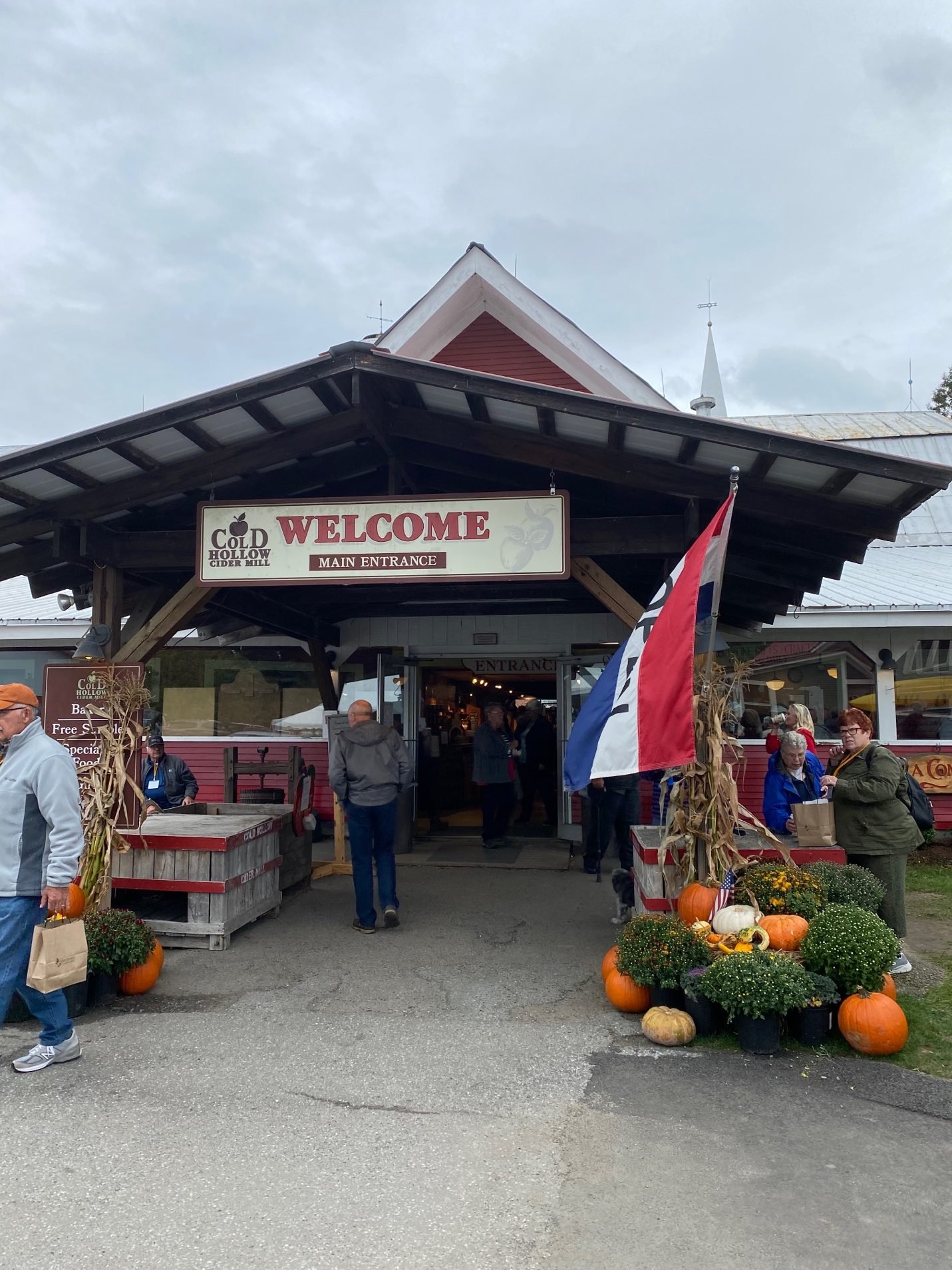 A sign with a flag and pumpkins in front of a store

Description automatically generated