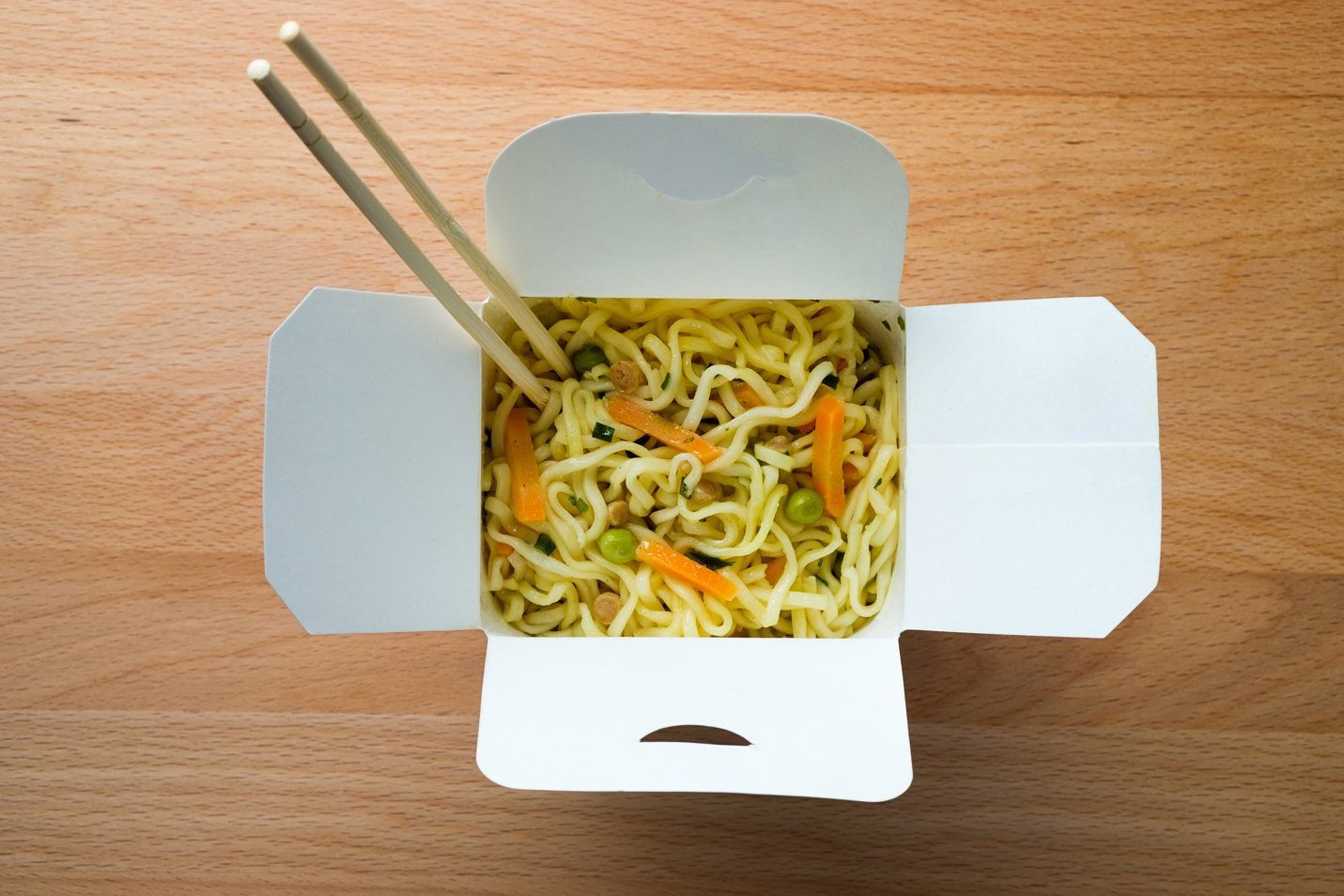 aerial view of noodles in takeaway box with chopsticks