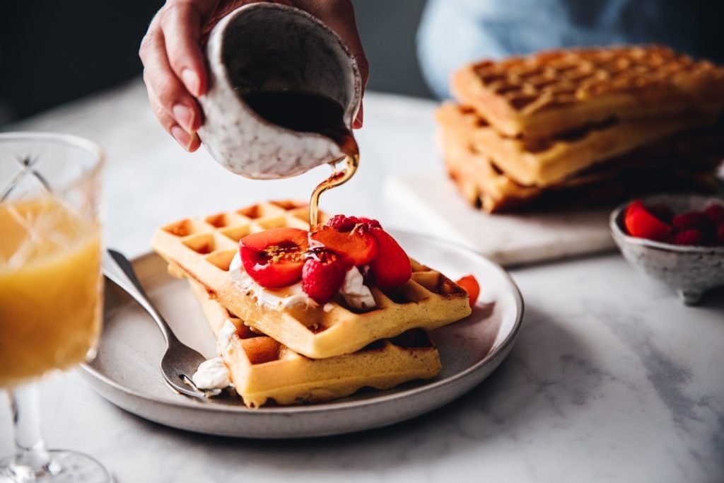 Hand pouring syrup on waffles