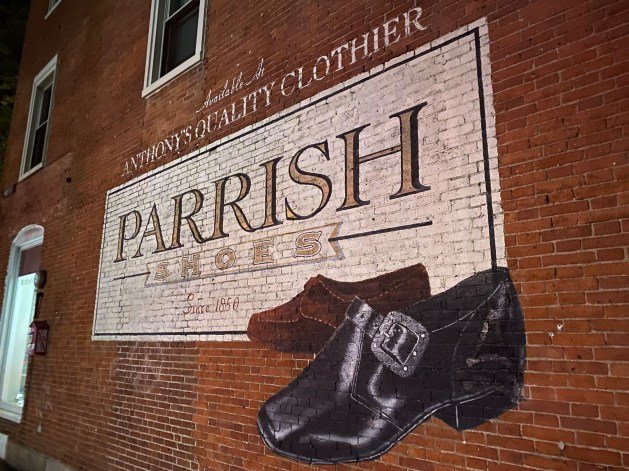 A brick wall with a painting of shoes and a belt

Description automatically generated