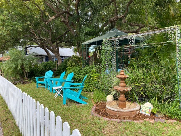 A lawn chair in front of a white fence

Description automatically generated