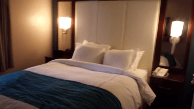 A bed with a blue blanket and pillows

Description automatically generated