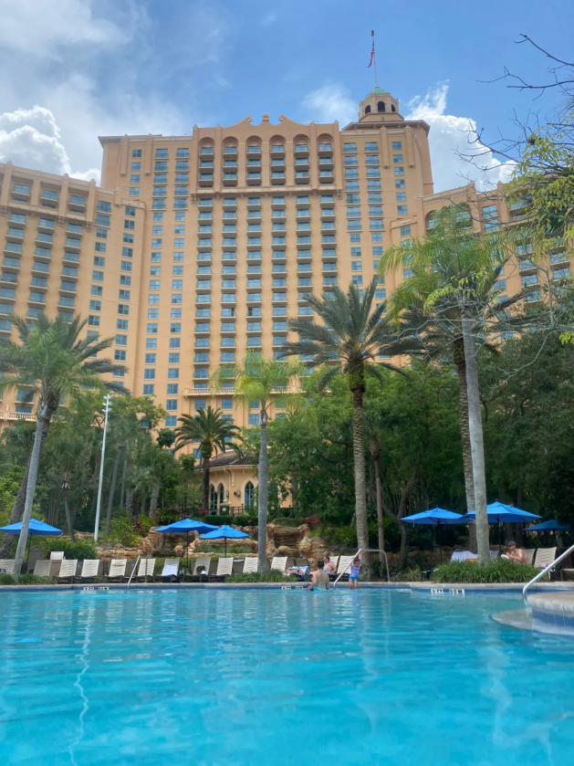 A pool with trees and a building in the background

Description automatically generated