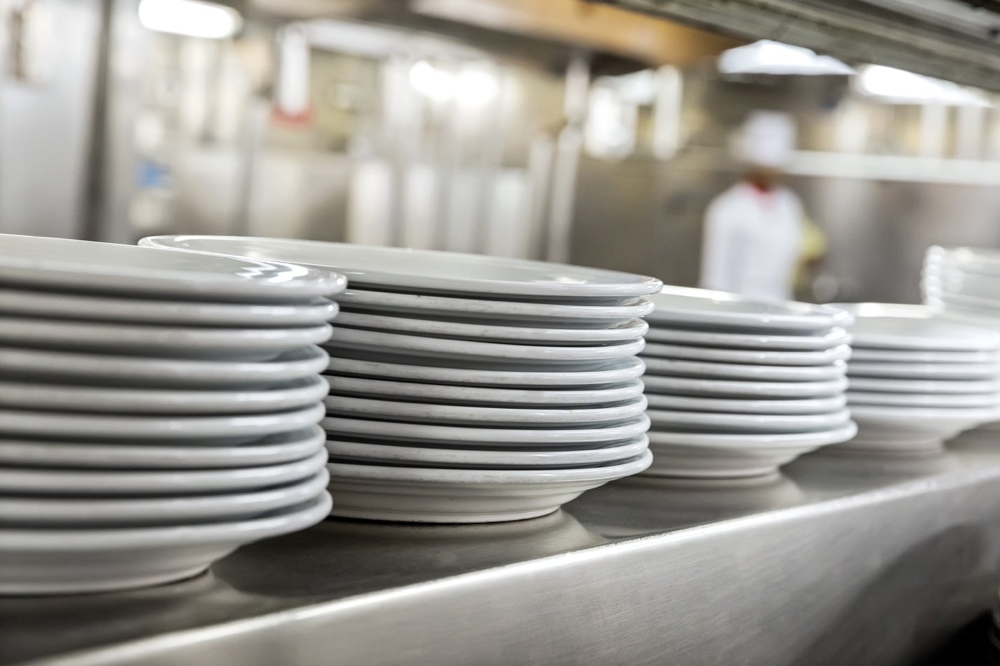 Rows of white dishes on shelf in restaurant kitchen